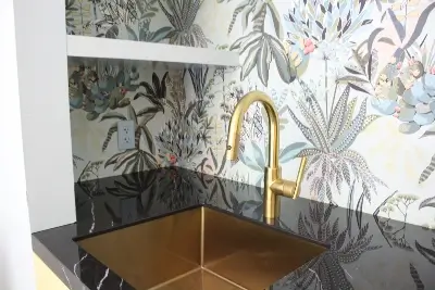 Black stone porcelain countertop in bathroom with gold sink, against floral print wallpaper in Vancouver WA and Portland OR - Crowley's Granite & Quartz