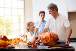 Family cooking Thanksgiving turkey together in a bright kitchen decorated for fall
