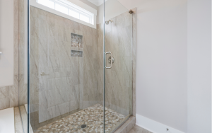 Tile shower with stone flooring and glass door